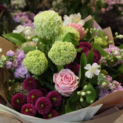 Designer's Choice - Summer - The summer bouquet contains a beautiful, seasonal selection of blooms in shades of pinks and greens, hand-tied ready to be placed into a vase.  Deluxe size pictured.